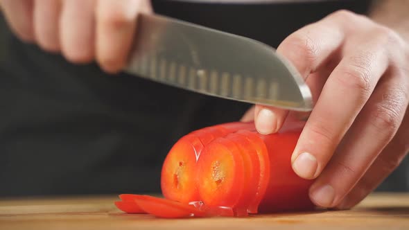 Slicing Sweet Peppers on a Chopping Board By a Chef Closeup of Men's Hands Cutting Red Peppers with