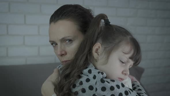 A Woman in Stress Hugs a Child.