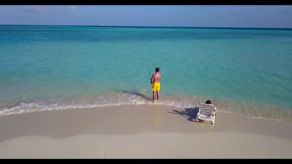 Young couple engaged on idyllic shore beach voyage by transparent water and clean sandy background o