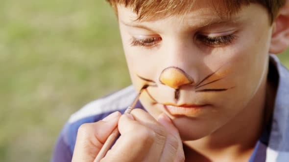 Woman applying paint on boy nose 4k