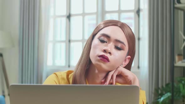 Bored Asian Young Transgender Woman Working With Laptop Computer In Living Room