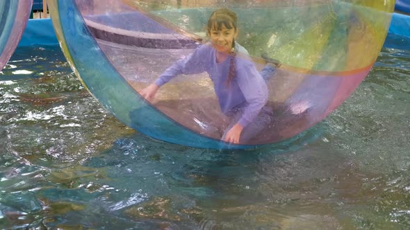 Happy child in an inflatable ball on the water.