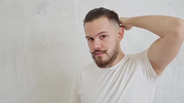 Young Handsome Man with Funny Mustache Wrapped Up Straightens His Hair