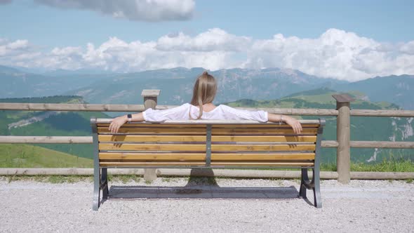 Girl Sitting on a Bench with Beautiful Mountain Panorama