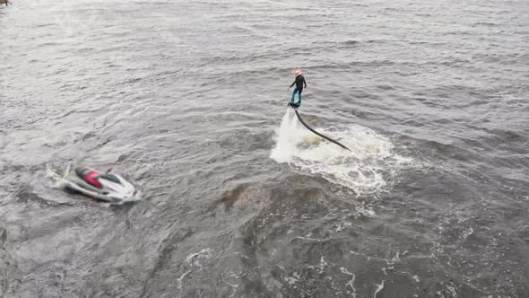 A Man Flying on the Flyboard and Other Man Riding Jet Ski in Circles  Aerial View