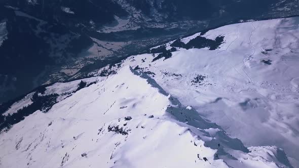 Aerial drone footage flying over the edge of a snowy mountain peak above the ski resort town in Verb