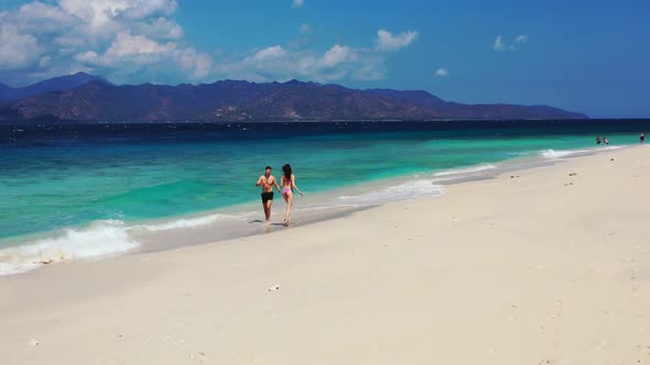 Two people tanning on perfect lagoon beach break by blue ocean and clean sandy background of Gili Ai