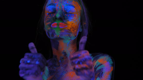 A Woman with Ultraviolet Drawings on Her Face and Body She Gives a Thumbs Up