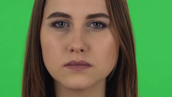 Woman Is Looking Straight and Blinking on Green Screen. Close Up