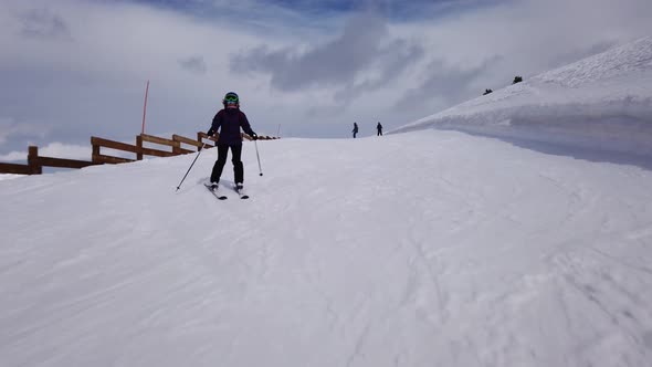 A shot from the front following a female skire descending a slope