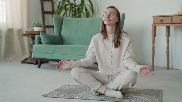 A Woman Practicing Yoga and Meditation in the Lotus Position Sitting on the Floor of at Home