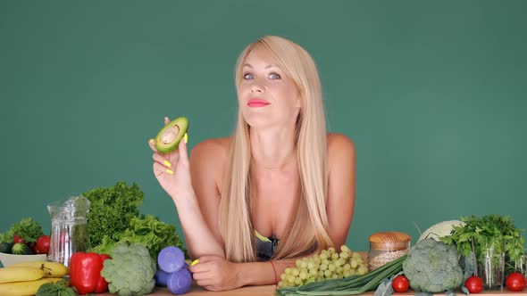 Girl Holding Avocado on the Table with Vegetables