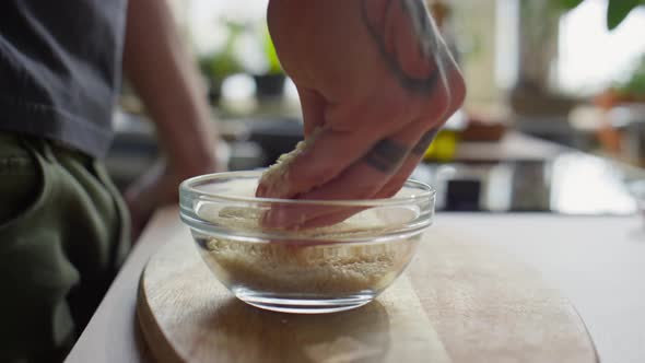 Hand of Chef Taking Sesame Seeds from Bowl