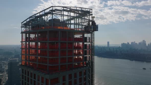 Aerial View of Upper Section of High Rise Building Under Construction Against Sky with Bright Clouds alt