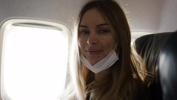 Portrait of Woman Taking Off Mask on Plane Looking to the Camera