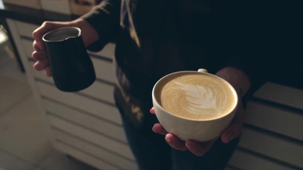 Close up of barista holding aromatic cappuccino. Coffee ready for sale.