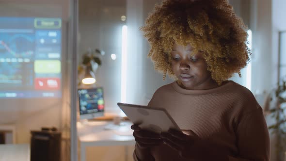 African American Woman Working on Tablet in Office at Night