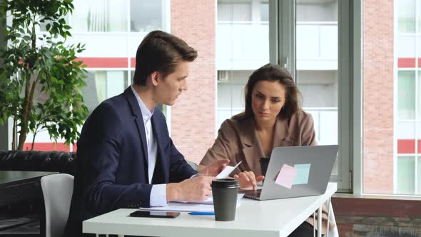 Man and woman work in modern office sitting at the table. Man and woman work