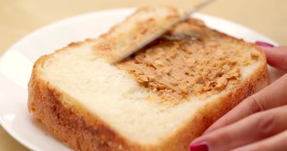 Apply peanut butter on white bread for breakfast