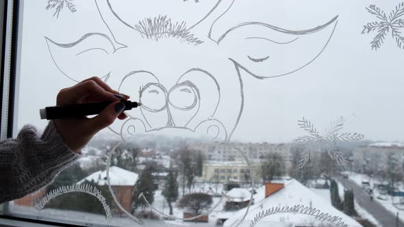 Female Hand Draws Christmas Holidays Decoration on Window Glass