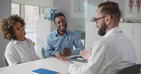 Portrait of Happy Smiling Couple Carefully Listening to Doctor Gynecologist