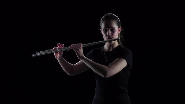 Woman Plays on Flute Slow Melody. Black Background, Slow Motion