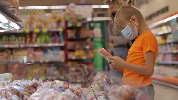 A single child in a mask buys food at the market