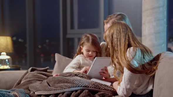 Caring Mother Spending Evening Time with Daughters on Sofa