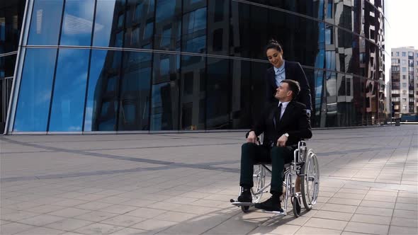 Handsome Businesswoman Cares for His Colleague in Wheelchair