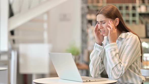 Stressed Young Latin Woman with Laptop Having Headache in Cafe