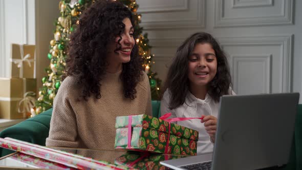 Young Mother and Her Little Daughter Celebrate Christmas or New Year Online Using a Video Call on a