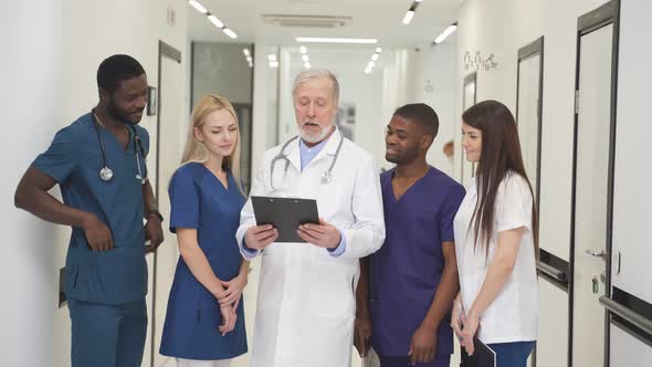 Elderly Doctor Teaches Young Medical Students Explain Tasks