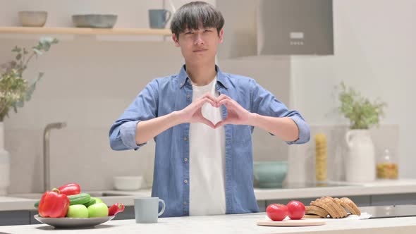 Young Asian Man Making Heart Shape By Hands While in Kitchen