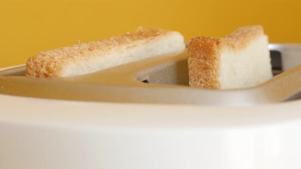 Bread pops up from electric toaster in front of yellow background 4K yellow