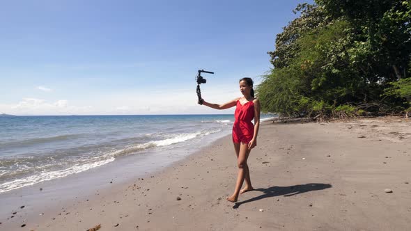 Young Millennial Social Media Influencer Walking on the Beach and Filming Video.