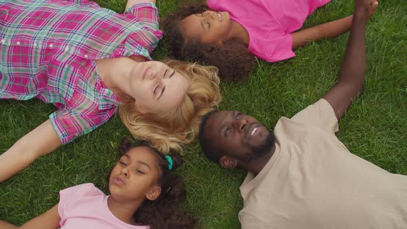 Diverse Family Lying Head To Head in Circle on Grass