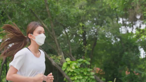 Asian young active sport woman wear mask run on street in public park.