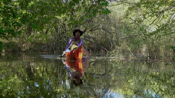 Cowboy in a Canoe Floats on the River in the Forest