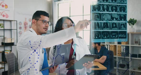 Male and Female Medical Workers Working with X-ray Scan in Medical Office on the Background