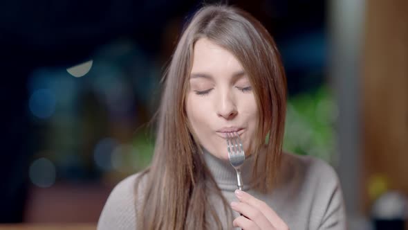 Front View Portrait of Beautiful Young Slim Woman Tasting Delicious Cooked Meat in Restaurant and