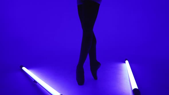 Ballet Dancer's Feet in Pointe Shoes Doing Pas Between Blue Neon Led Lamps