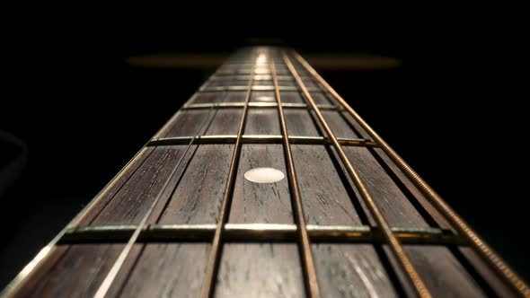 Camera Pans Over the Fretboard of a Classical Acoustic Guitar Against a Black Background