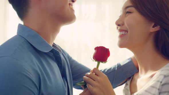 Asian young man surprise and give rose flower to beautiful girlfriend.