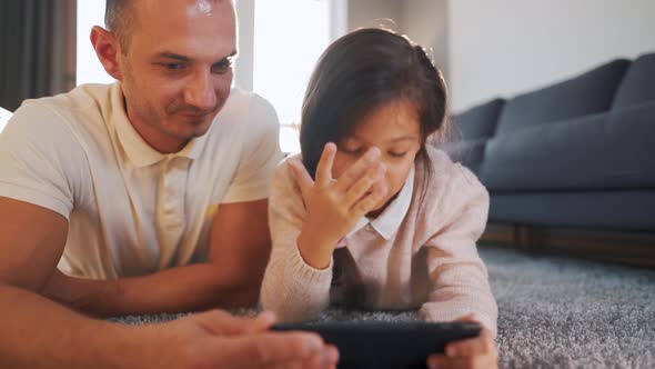 Happy Smiling Father and Daughter Enjoying Time Together and Using a Tablet for Family Entertainment