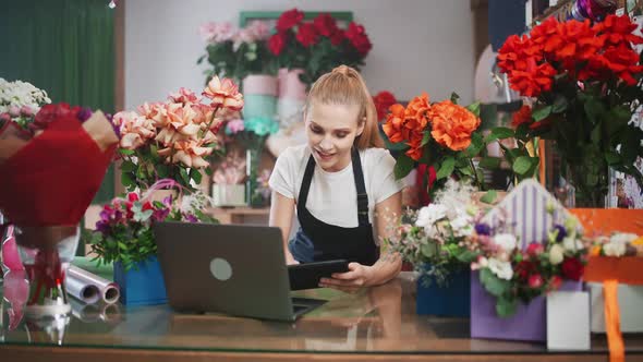 Florist Woman Discusses the Order By Talking on Video Call Using a Laptop and Screen Tablet in a