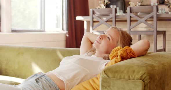 Young calm woman relaxing on comfortable couch at home, resting on sofa