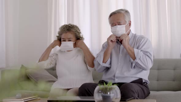 Couple Asian elderly wear masks stay in living room.