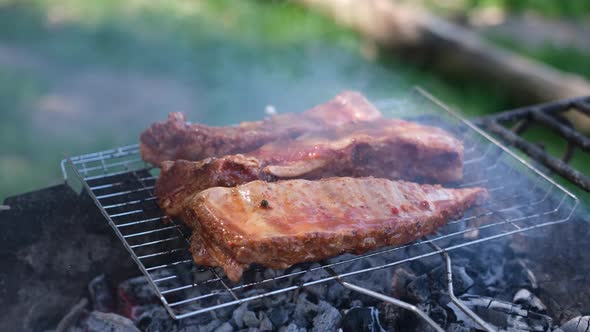 Delicious Beef or Pork Ribs Frying on a Charcoal Grill Being Covered with Red Gravy Sauce Brush