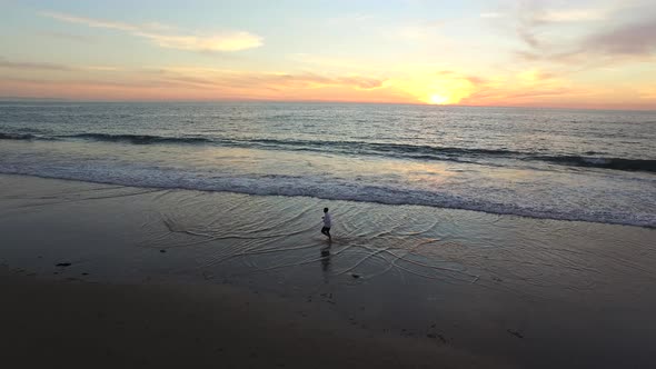 Aerial shot of young man running on the beach.