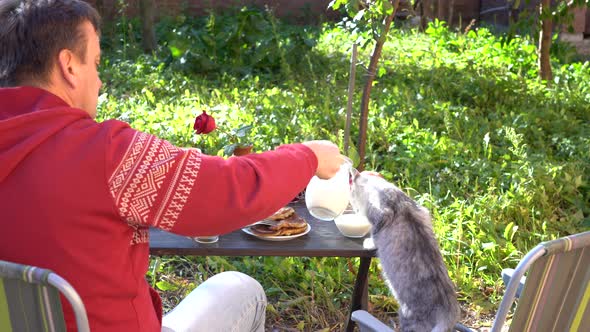 Joint breakfast of a man and a cat in the autumn garden, close up